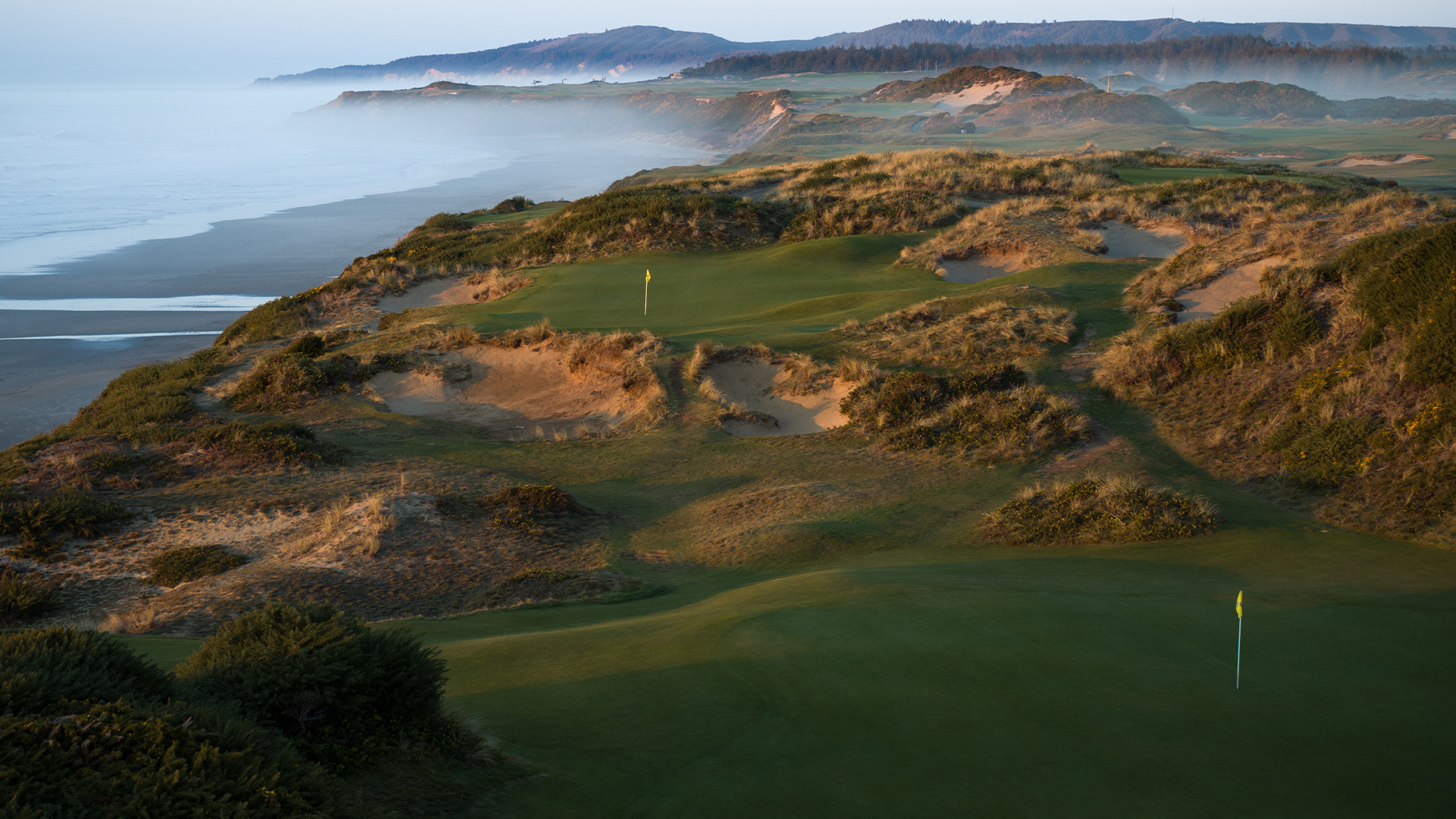 Rumpled dunes and blown-out bunkers at Pacific Dunes with the Pacific and sea mist behind